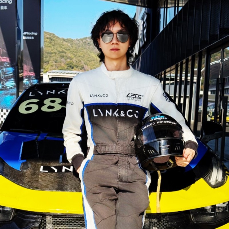 Dantong Li in a racing suit, holding a helmet beside a race car